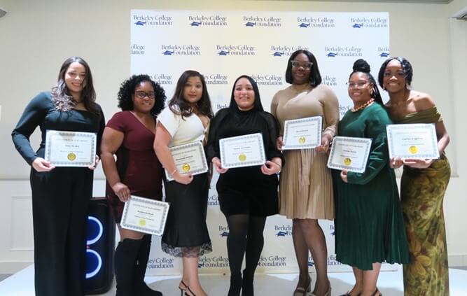 A group of students hold certificates, smile, and pose for the camera