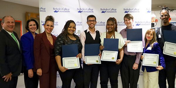 Diverse students holding certificates against a plain background